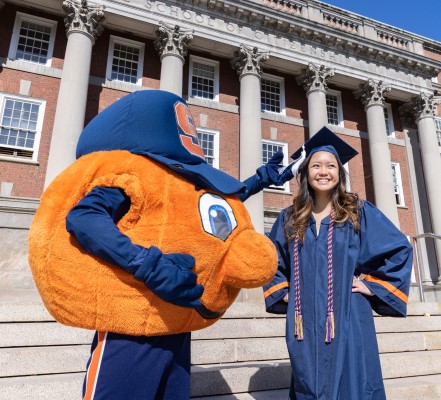 2022 Syracuse University Graduate in their Cap and Gown with Otto on Campus