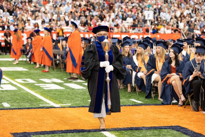 Syracuse University mace bearer, Bea González, processes down the 50-yard line in the JMA Wireless Dome opening the 2022 Commencement ceremony