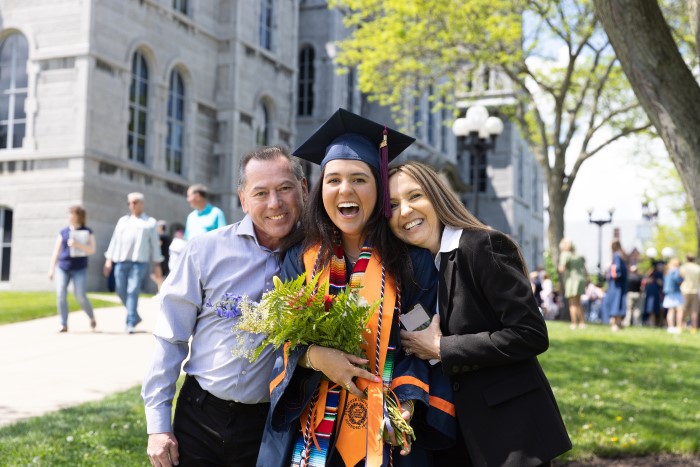 Class of 2022 graduate poses with her parents on campus next to the Hall of Languages