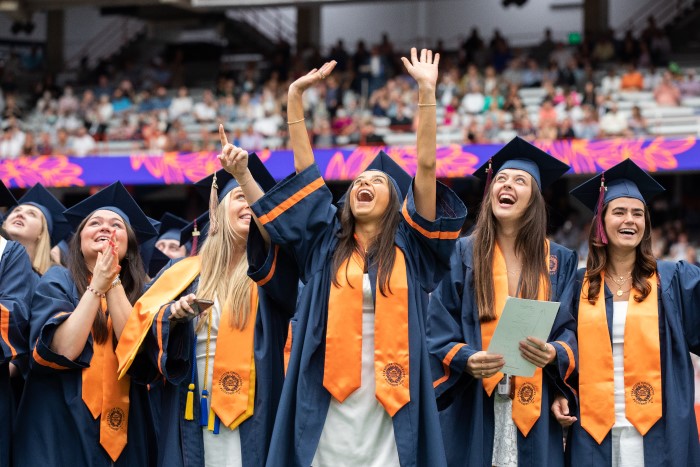 A group of graduates stand and cheer during the 2022 Commencement ceremony